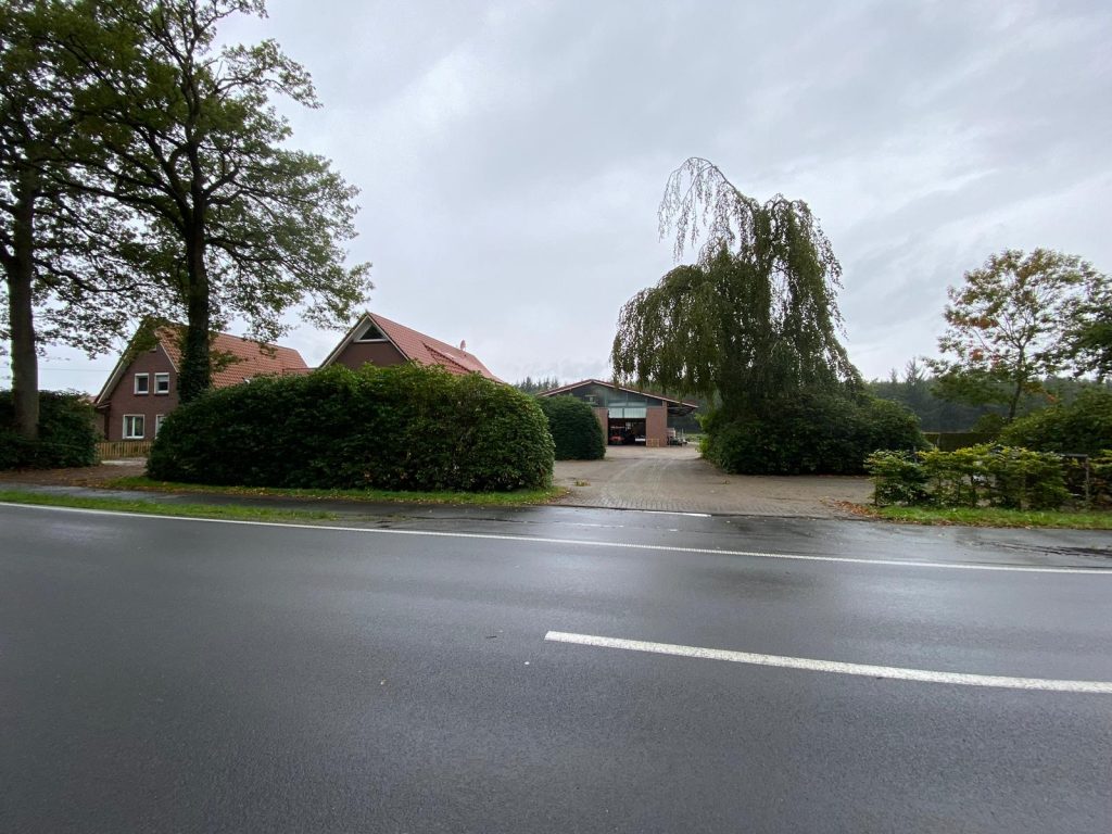Außenansicht von Haus Willbrok mit zwei Gebäuden und einem großen Baum, aufgenommen von der Straße.