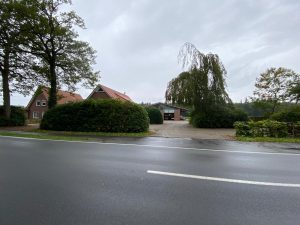 Außenansicht von Haus Willbrok mit zwei Gebäuden und einem großen Baum, aufgenommen von der Straße.