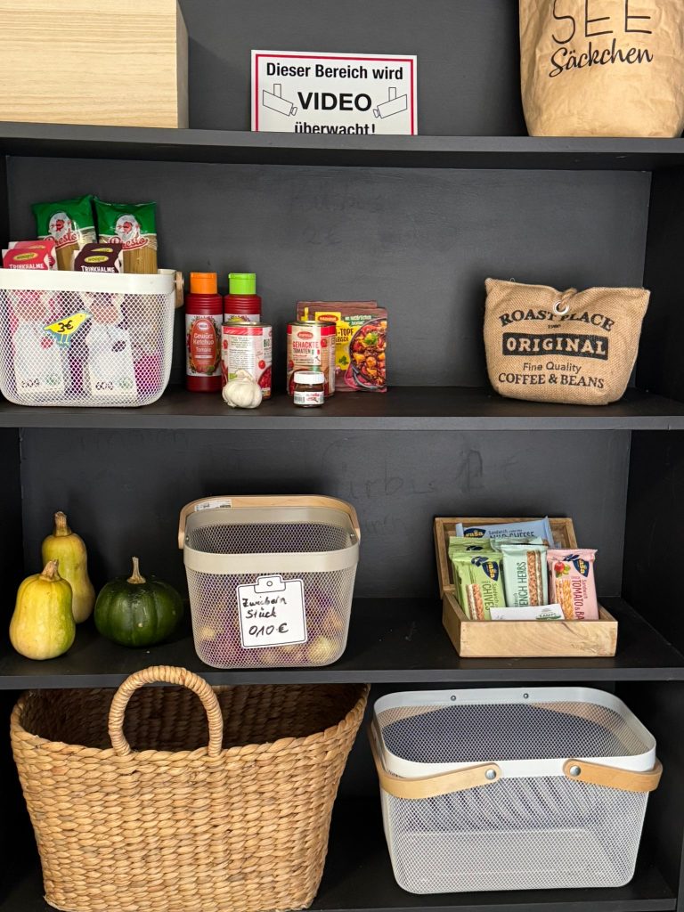 Regal im Hofladen Tante Willbrok mit verschiedenen Produkten wie Saucen, Gewürzen, Kaffee und frischem Gemüse.