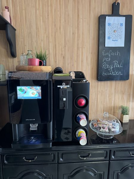 Kaffeemaschine im Hofladen Tante Willbrok mit einer Auswahl an Kaffeebechern und einer PayPal-Zahlungsmöglichkeit.
